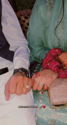 a man and woman sitting next to each other with their hands on the bride's wrist