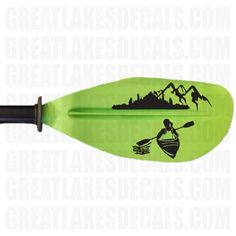 a green paddle with a black silhouette of a person in a boat on the water