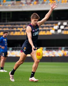 a man kicking a yellow ball on top of a field