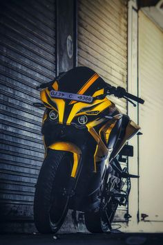 a yellow and black motorcycle parked in front of a garage