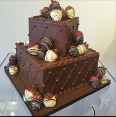 a triple layer chocolate cake with strawberries and chocolates on the top, in a display case