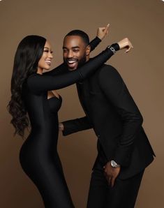 a man and woman in black outfits posing for the camera with their arms around each other