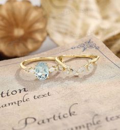 two gold rings with blue topazte and white diamonds sitting on an old book