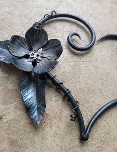 a metal flower is attached to a hook on the floor with an iron rod and two hooks