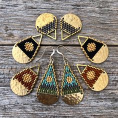 six pairs of earrings on top of a wooden table next to some other pieces of jewelry