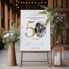 a sign that says, welcome to the 50th wedding anniversary and is next to two vases with flowers