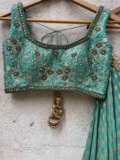 A three-piece jade green zari lehenga set from the Priti Sahni collection. This beautiful georgette small butti green lehenga with a heavy border of sequin, pearl and zari work detail with green accent is paired with a raw silk green blouse with sequin and zardosi embroidery detail all over. The lehenga has side hanging ball tassels to the waistline. And the blouse has a sequins tassel tie-up at the back. This outfit is completed with a sequin tulle dupatta with jade green accent in net material Green Embellished Pre-draped Saree For Wedding, Green Anarkali Set With Unstitched Blouse For Designer Events, Green Anarkali Set For Designer Wear, Elegant Green Dola Silk Choli, Transitional Green Dola Silk Choli, Designer Green Dola Silk Choli, Green Choli With Zari Work For Transitional Season, Green Chinon Pre-draped Saree For Navratri, Green Dola Silk Pre-draped Saree For Reception