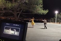 two people are dancing in the street at night with one person holding his hand out