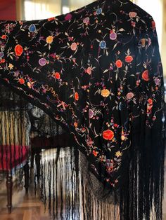 A magnificent Manton de Manila shawl made of black silk crepe fabric then heavily embroidered with colourful silk thread.  The embroidery is so well done you can barely tell which is the right side. The shawl is covered in embroidered flowers and leaves and around the edges are unusual depictions of musical symbols and bows. Quite a spectacular piece. In excellent condition  Measures 42" x 42" with a 20" woven fringe Silk Shawl With Intricate Embroidery, Multicolor Embroidered Shawl Scarf, Multicolor Embroidered Shawl Scarves, Embroidered Silk Shawl Scarf, Black Embroidered Silk Shawl, Silk Shawl With Multicolor Embroidery, Traditional Black Floral Print Dupatta, Multicolor Embroidered Silk Shawl, Intricate Embroidery Shawl Scarf