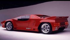 a red sports car parked in front of a white wall