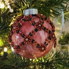 a pink ornament hanging from a christmas tree with beads and beadwork