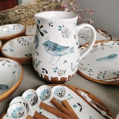 a table topped with plates and cups filled with birds on them next to a basket