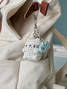 a white bag with a small crocheted keychain hanging from it's side