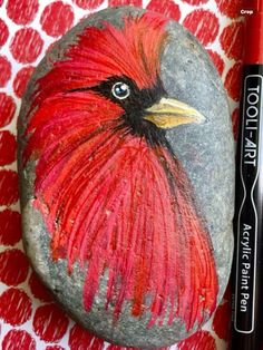 a rock with a red bird painted on it and a black marker next to it