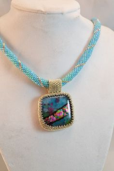 This wonderful hand beaded pendant can be worn with anything, the dichroic glass pendant with shades of purple and turquoise is highlighted with silver color and turquoise beads. Perfect as a gift for yourself, or that special someone, this necklace will come to you in a gift box! Designed and hand beaded by me in my Las Vegas studio, this piece is one of a kind. Pendant measures about 1 1/4 inches tall and across, and the necklace measures approximately 20 inches long. For more of my handmade j Handmade Glass Pendant Beaded Necklace, Handmade Turquoise Glass Beaded Necklaces, Handmade Turquoise Glass Beaded Necklace, Turquoise Beaded Glass Jewelry, Blue Beaded Gems And Cabochons For Gift, Iridescent Beaded Jewelry As A Gift, Iridescent Beaded Jewelry For Gift, Handmade Glass Square Pendant Jewelry, Handmade Square Glass Pendant Jewelry