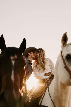 a woman riding on the back of a white horse next to a brown and black horse