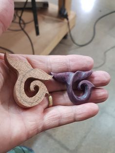 a person holding two small wooden pieces in their hand, one is purple and the other is brown