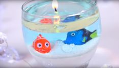 a candle that is inside of a glass bowl with some water and fish in it