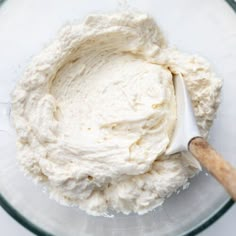 a glass bowl filled with whipped cream next to a wooden spoon