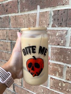 a hand holding a drink with a skull on it and the words bite me written in black