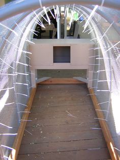 the inside of an enclosed area with wood flooring and metal mesh covering it's walls