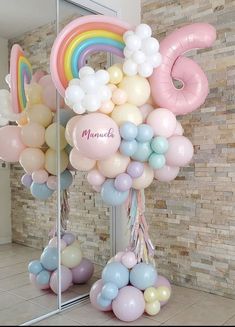 there are many balloons in the shape of animals and rainbows on this display stand