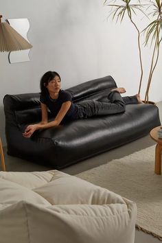 a woman laying on top of a black couch in a living room