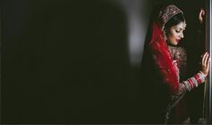 a woman in a red and white bridal outfit is looking out the window at something