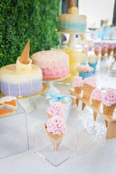 ice cream cones with pink frosting and sprinkles are on the table