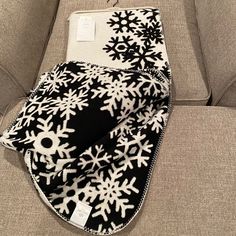 a black and white snowflake print blanket on a couch with the tag attached to it