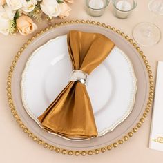 a place setting with gold napkins and white plates