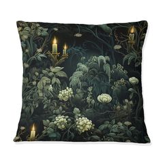 a black pillow with candles in the middle of it and flowers on the side, surrounded by greenery