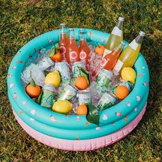 an inflatable pool filled with drinks and lemons on top of green grass