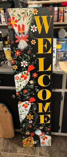 a sign that says welcome with roosters and flowers on it in front of a kitchen counter