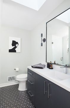 a bathroom with a white toilet sitting next to a sink under a large framed mirror