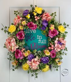 a wreath with flowers on it that says live in the full bloom and is hanging on a door