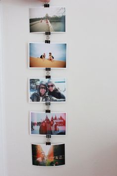 a person holding up several polaroid photos on a wall