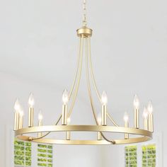 a gold chandelier with six candles hanging from the ceiling and green shutters