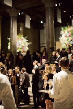 a group of people standing around each other in a room filled with tables and chairs