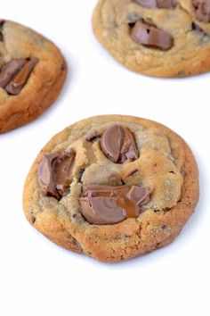 three chocolate chip cookies on a white surface