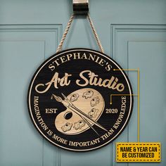 a sign hanging from the side of a blue door that says, stephanie's art studio