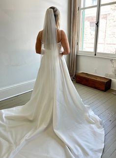 a woman in a wedding dress looking out the window