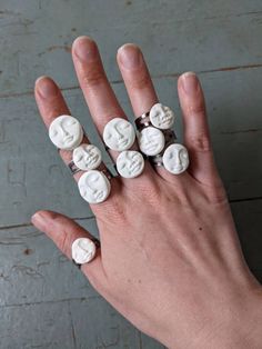 a woman's hand with five white buttons on it, all in the shape of faces