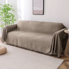 a living room with a couch covered in a blanket next to a table and potted plant