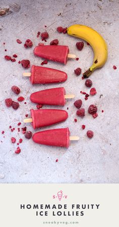 four popsicles with raspberries and bananas on them sitting next to a banana