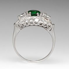 This gorgeous vintage ring is centered with one (1) round cut natural Tsavorite garnet set into a four-split prong setting. The Tsavorite is flanked to each side by one (1) prong set old European cut diamond. The ring is also bordered with eighteen (18) bead and prong set round brilliant cut diamonds. The ring measures 11.6mm at the top, rises 6.8mm above the finger, and tapers to 1.5mm wide by 0.8mm thick at the base of the shank. It is crafted in platinum and is currently a size 6. One of the accents diamonds is lightly chipped. Tsavorite Garnet Ring, Tsavorite Garnet, Garnet Ring, European Cut Diamonds, Garnet Rings, One 1, Vintage Ring, Round Brilliant Cut Diamond, Round Brilliant