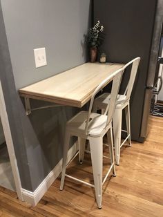 three stools sit at the edge of a table in front of a gray wall