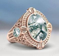 this is an image of a ring with a green stone in the center and leaves on it