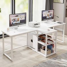 two computer screens sitting on top of a white desk in front of a large window