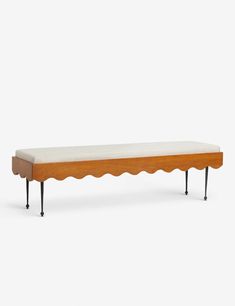 a wooden bench with scalloped legs and a white cushion